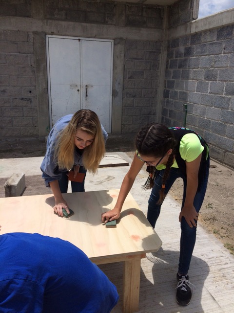 Two of the youth from the York  team, Maiah and Sara, sand down one of the tables built for the casa.